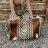 Woman holding a patterned brown leather tote bag outdoors