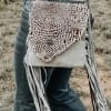 Patterned leather fringe bag worn over jeans outdoors