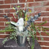 Mixed floral arrangement in a metal vase with a decorative white bird.