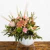 Pink and peach floral arrangement in a white bowl vase