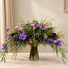 Large purple and pink floral arrangement in a clear glass vase