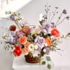Mixed bouquet of roses and daisies in a woven basket