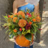 Orange and red floral arrangement in a pumpkin container