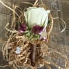 White rose boutonniere with purple flowers in a clear plastic box