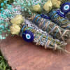 Bundles of dried flowers tied with blue cord and evil eye charms