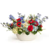 Mixed bouquet in a white bowl vase with red, blue, and white flowers