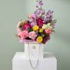 Mixed bouquet of pink, yellow, and lavender flowers in a white box