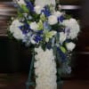 White floral cross on an easel with blue and green accents