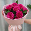 Bouquet of bright pink roses wrapped in pale pink paper