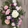 Pink and white mixed flower bouquet with greenery on a wood floor