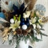 Soft white and blue flowers mixed with winter greens, pinecones and natural