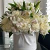 White floral arrangement in a round hat box with a satin ribbon