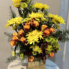A vibrant mix of yellow chrysanthemums, roses, hydrangeas, and seasonal greenery, designed