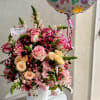 Pink and cream rose bouquet in a white vase with a birthday balloon