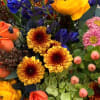 Mixed bouquet with orange and yellow roses, blue flowers, and pink blooms