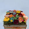 Colorful mixed flower arrangement in a wooden box with an orange ribbon