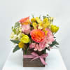 Colorful flower arrangement in a wooden box with a pink ribbon