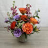 A bold burst of orange roses framed by purple and pink blooms-Tuscan
