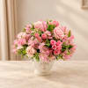 Pink roses and lilies arranged in a white ceramic vase