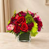 Red roses and pink flowers arranged in a square glass vase