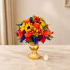 Bright mixed bouquet in a gold vase with a small candle nearby