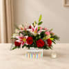 Red roses and pink lilies in a printed container on a table