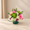 Pink and white flower arrangement in a green glass vase