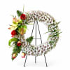 Floral wreath on a black stand with white blooms and red roses