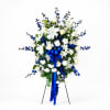 Standing floral spray with white lilies, roses, and blue flowers on a stand