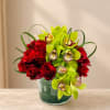 Red roses and green orchids in a glass vase
