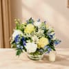 Bouquet of yellow, white, and blue flowers in a glass bowl vase