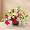 Pink and white mixed flower arrangement in a square glass vase