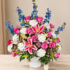 Pink roses, white lilies, and blue flowers in a white vase