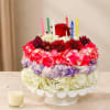 Round floral cake with candles and a red rose topper on a pedestal stand