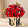 Red roses arranged in a black round box with a cream ribbon and butterfly accents