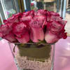 Pink roses arranged in a square glass vase with white stones