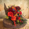 Orange roses and burgundy mums arranged in a rustic basket.