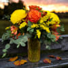 Orange and yellow flower arrangement in a tall glass vase