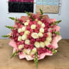 Bouquet of pink and cream roses with pink snapdragons wrapped in pink paper