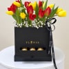 Red and yellow tulips in a black gift box with chocolates and ribbon