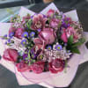 A lush mix of pink roses and mauve orchids gives this flower