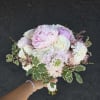 Handheld bouquet of pale pink and white flowers with variegated greenery