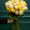 Handheld bouquet of pale yellow, cream, and blush roses