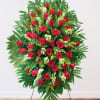Standing spray of red roses with white accents and tropical greenery