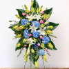 Standing floral spray with blue hydrangeas, white lilies, and yellow snapdragons