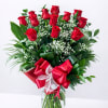Red roses arranged in a clear glass vase with a red ribbon bow