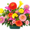 Colorful mixed bouquet with calla lilies, dahlias, roses, and a green vase