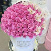 Pink roses and white orchids arranged in a white hat box