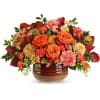 Orange roses and mixed fall flowers in a brown ceramic vase