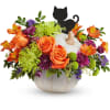Orange and purple flower arrangement in a white pumpkin vase with a black cat topper